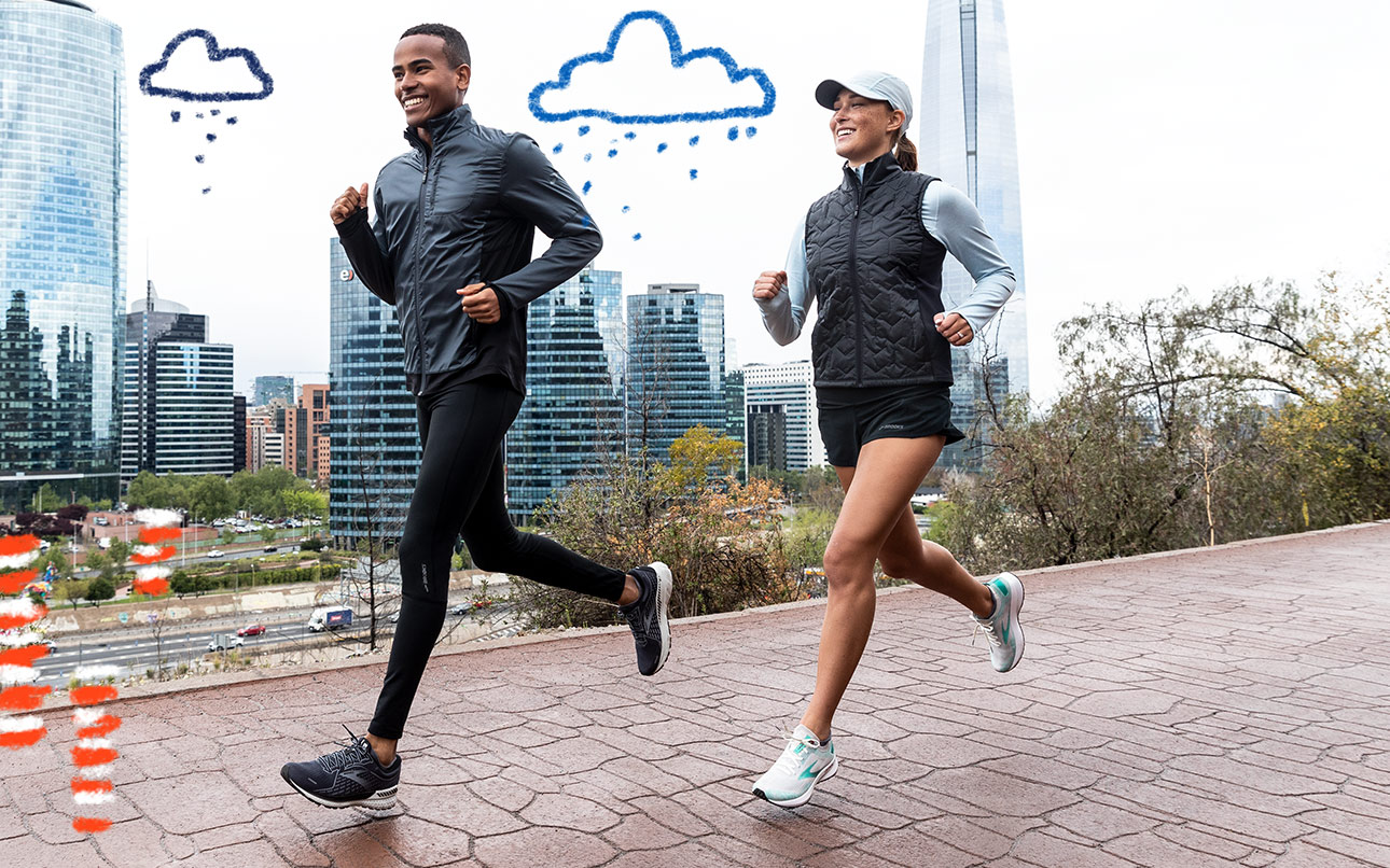 A man and woman run in cloudy weather with a cityscape in the background.