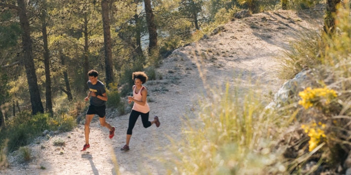 Two runners team up for a long run through a forested area.