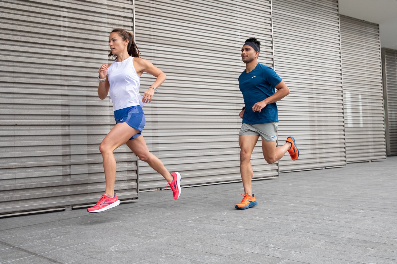 Zwei Models tragen beim Laufen Bekleidung und Schuhe von Brooks