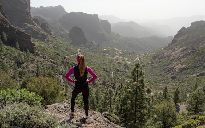 Runner standing on a lookout point over a valley