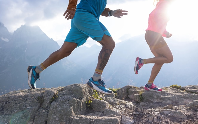 Low-angle shot of two runners on a rocky trail.