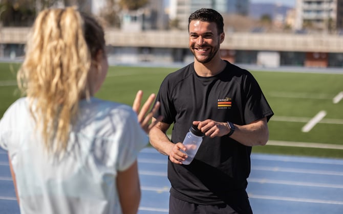 Two runners chatting and drinking water after a long run