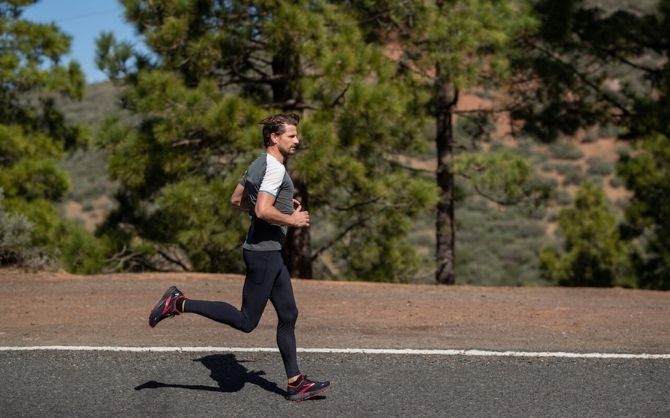 Side view of a runner on a tree-lined road.