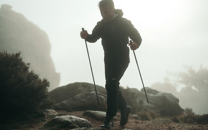 Runner climbing up a mountain with trekking poles