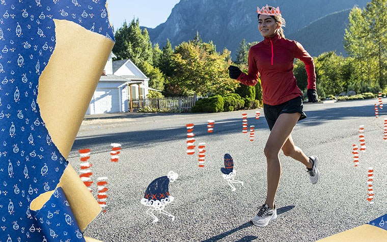 A runner wearing a red long-sleeve half-zip and shorts runs on a road with mountains in the background.