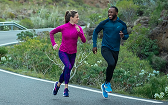 Gros plan sur les jambes de deux runners courant sur une surface pavée de dalles à motifs.