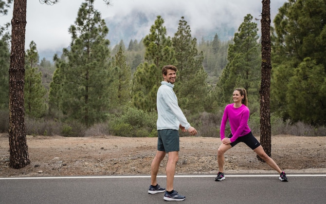 Deux coureurs effectuent des exercices dynamiques pour s’échauffer avant de courir.