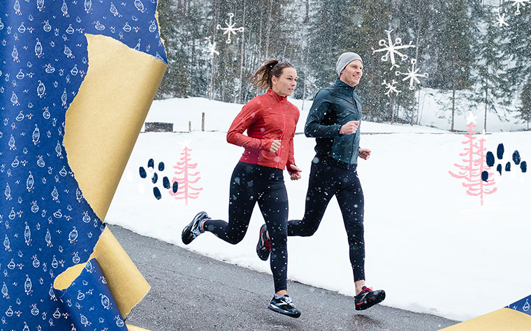 Photo of a man and woman running on a road with snow in the background