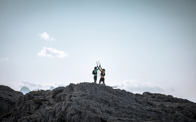 Trail runners high fiving each other on top of a mountain