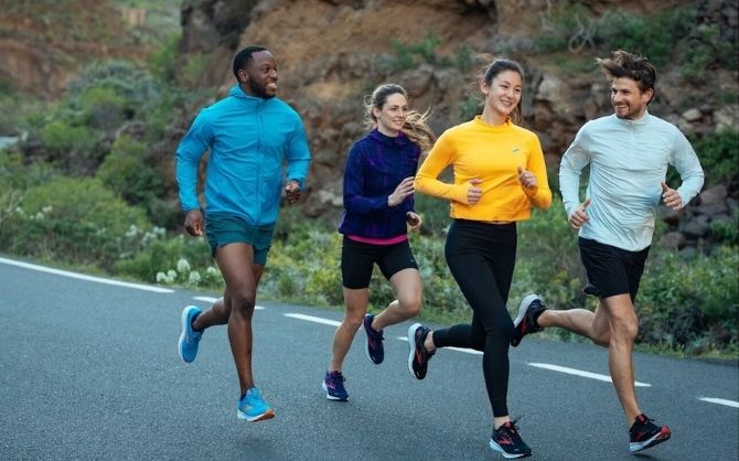 Un groupe de quatre coureurs rit ensemble pendant une course de groupe.