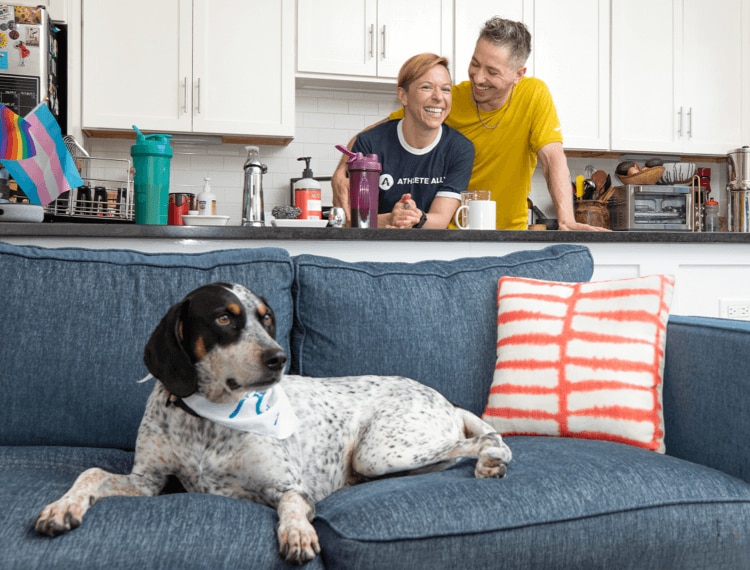 A dog on the couch with Anne and Shane in the background