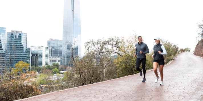 Two runners head out together on a peaceful path outside a city.