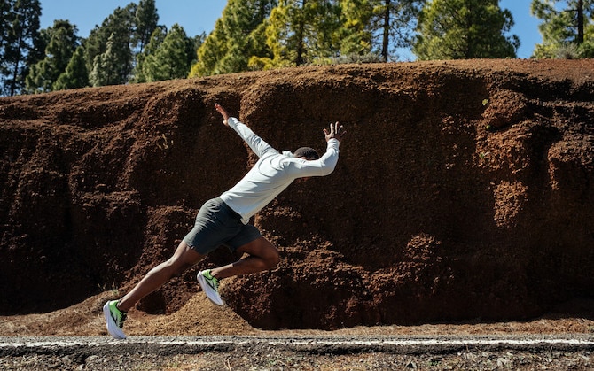 Side view of a runner launching into their stride on a road.