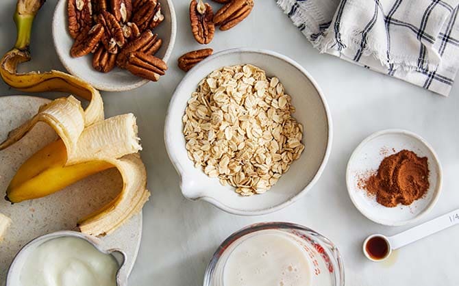 Plates with oatmeal, banana, pecan nuts and cinnamon