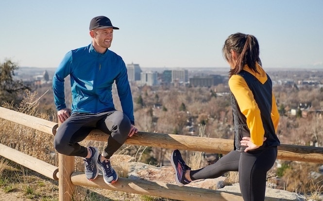 Deux runners discutent et étirent leurs ischiojambiers avant un run.