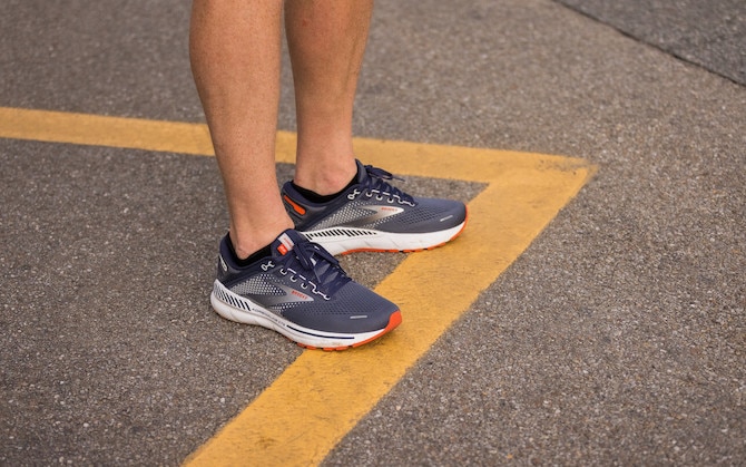 Low-angle shot of two people wearing running sneakers while walking.