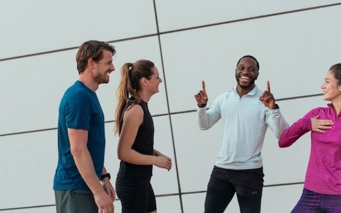 Un groupe de quatre coureurs rit ensemble après une course de groupe.