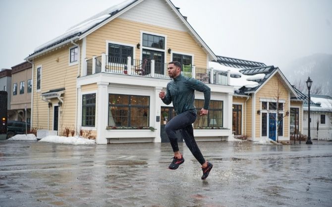 Coureur devant un grand bâtiment jaune sous la pluie