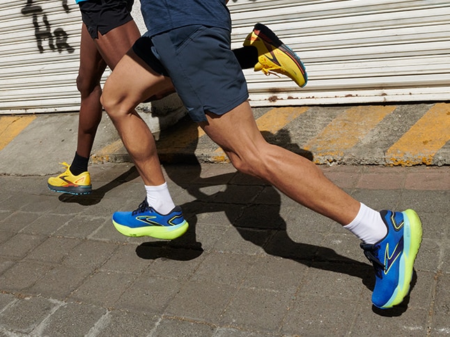 Immagine a mezza figura di due uomini che indossano le scarpe di Brooks Running