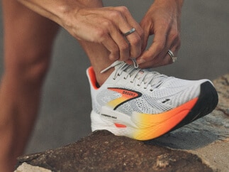 Gros plan d’un coureur qui lace une chaussure Brooks