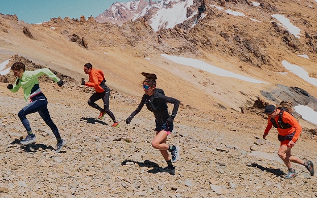 Cuatro trail runners subiendo por un terreno rocoso